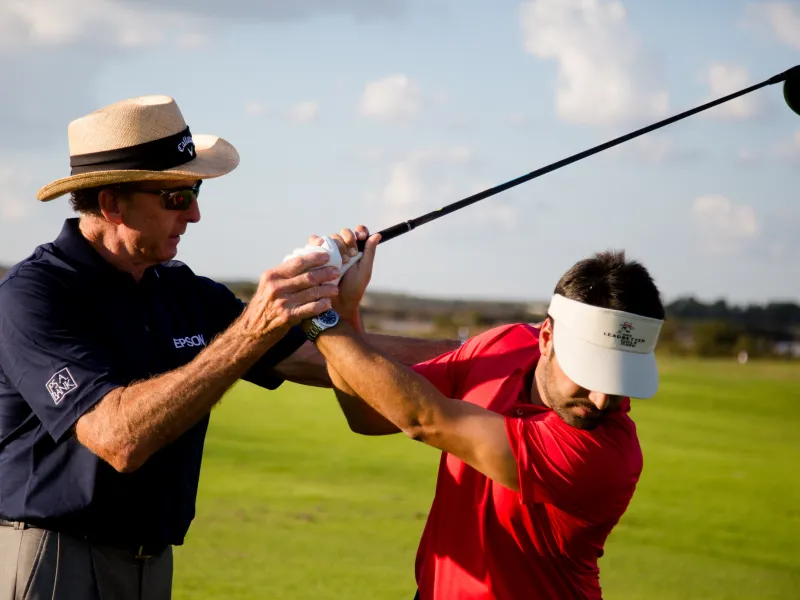 Golf instructor giving lessons to man in red shirt