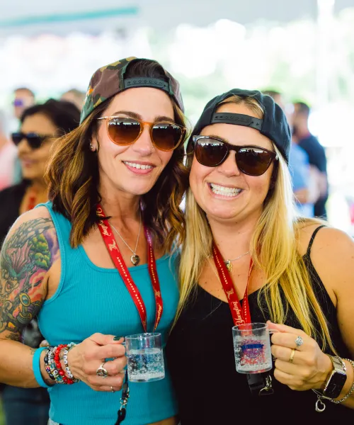 Two women holding mini beer samplers. 