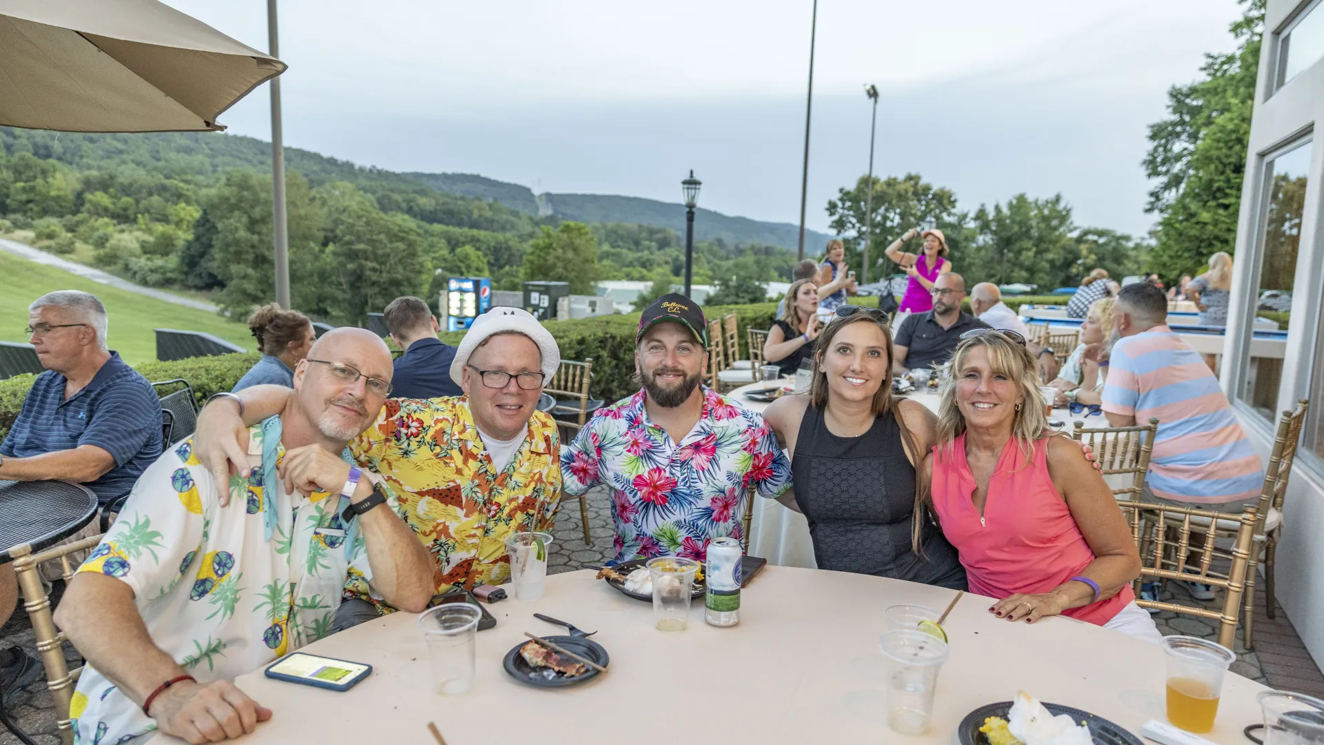 Group of people sitting at table with mountain view behind them.