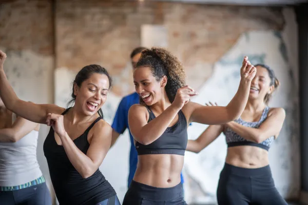 Women bumping hips during dance based workout.